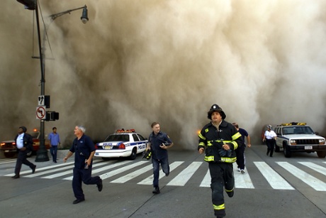 Policemen and firemen run as a huge dust cloud caused by the collapse of one of the twin towers engulfs downtown Manhattan.