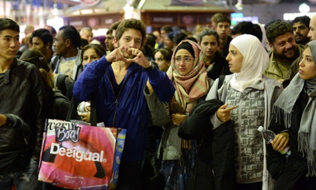 After arriving by train from Budapest, a refugee makes a heart with his hands at the central station in Munich, 12 September 2015