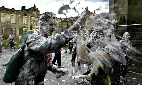 A foam-covered fresher spraying someone in foam at St Andrews University.