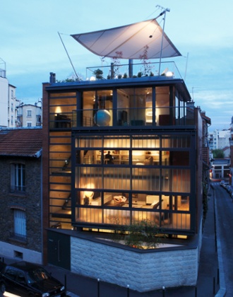 The multistorey house, with a stone wall beneath it, including a roof terrace with square suspended canopy