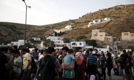 Refugees and migrants wait to board a passenger ship heading to the island of Samos, Greece.