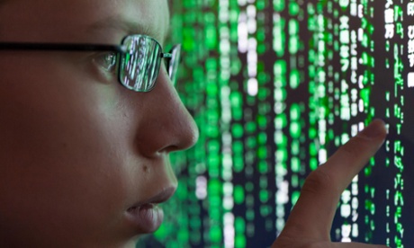 A young man watches futuristic symbols on a computer screen