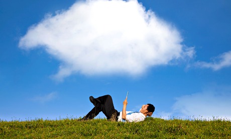 Businessman lying on grass with a tablet