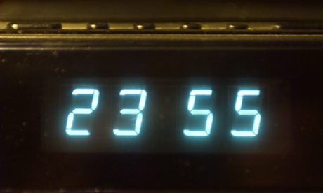 digital clock showing five to midnight