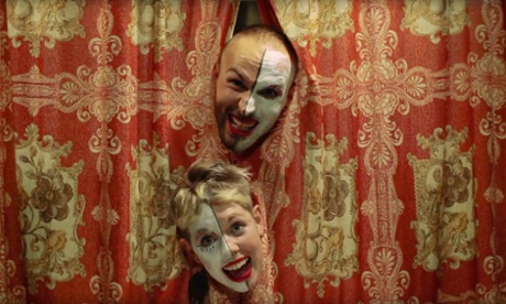 Emma Jaay and Martin Butz push their half-painted faces through a theatre curtain