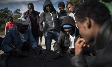 Men play dominoes at a migrant camp in Calais