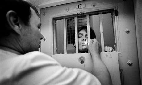 A prison officer lights a prisoner's cigarette through the cell bars in Pentonville prison, London.