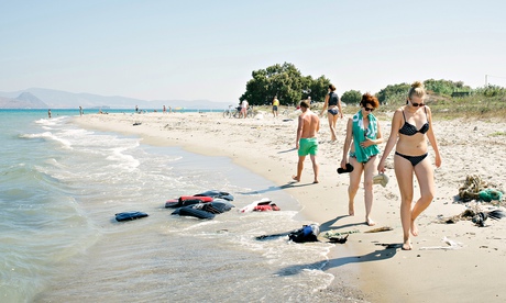 Tourists walk along a beach in Kos