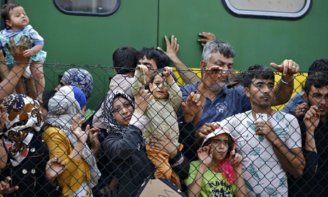 Migrants stand in front of the Bicske railway station in Bicske