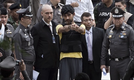 A foreign suspect identified by Thai authorities as Yusufu Mieraili points towards the Erawan shrine during a re-enactment.