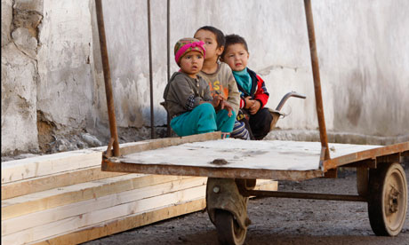 Ethnic Uzbek children sit at their destroyed house in Osh