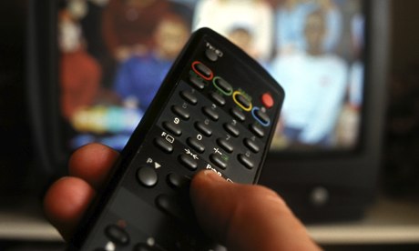 hand holding TV remote control with television in background