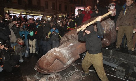 A protester swings a hammer at the fallen statue of Lenin in central Kiev