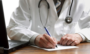 Doctor writing next to computer