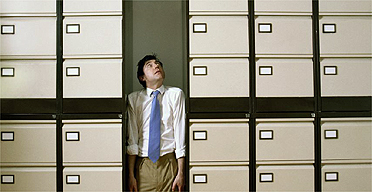 Stressed office worker squashed by filing cabinets