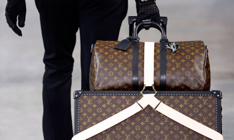 A model carries Louis Vuitton suitcases