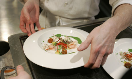 A chef places a dish of food on a tray