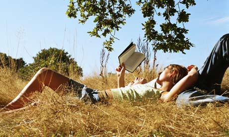 Young couple reading a book under a tree