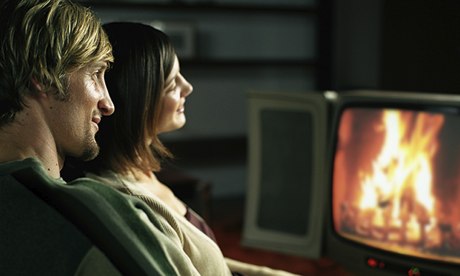 A couple watching a log fire on television