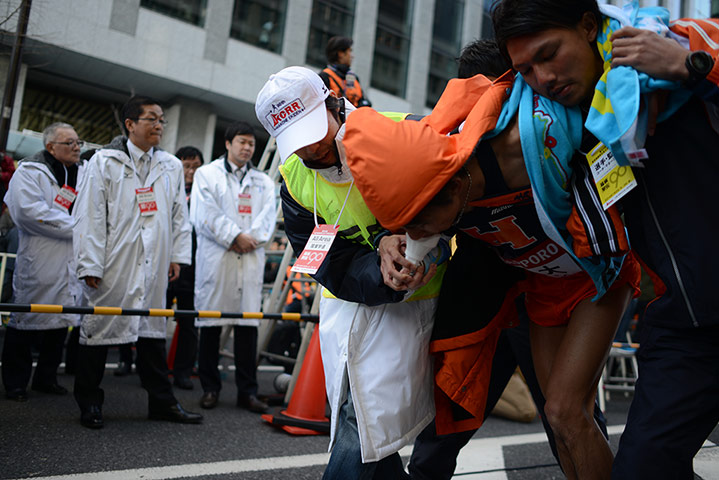 Hakone ekiden: One exhausted runner is given air by a marshal after finishing the race