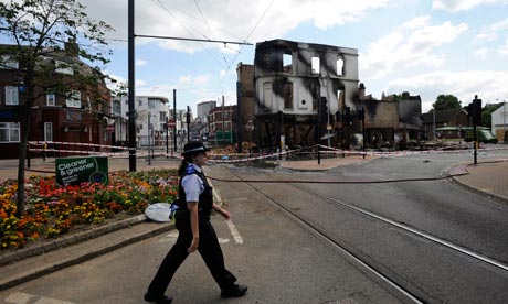 London riots: a police officer passes the remains of a burnt out furniture shop in Croydon. Photograph: Facundo Arrizabalaga/EPA