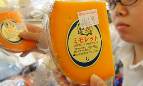 Salesperson replenishes stocks of French cheese 