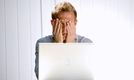 Man rubs eyes in front of his laptop