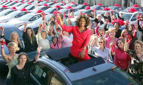 Talk show host Oprah Winfrey sits atop a Pontiac G6 surrounded by some of the 276 audience members who each received one of the cars to celebrate the start of her 19th season in 2004. Photograph: Bob Davis/AP