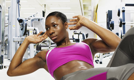 A young woman doing sit-ups in gym