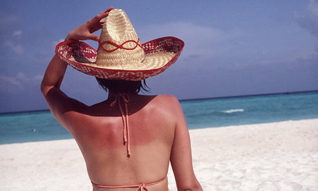 A woman sitting on a beach sunbathing