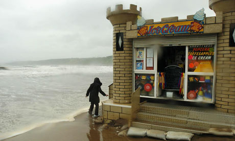 British summers: A seafront shopkeeper braves the storm to check her premises in Scarborough in July