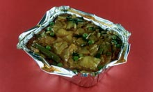 A takeaway vegetable curry in a tin foil tray