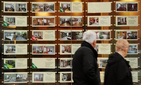 An older couple walk past an estate agent's window