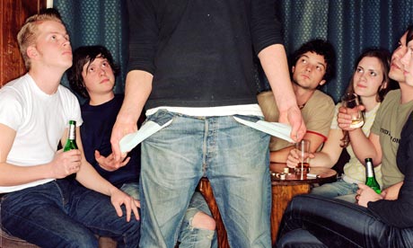 A student holds out his empy pockets in front of his friends in a bar