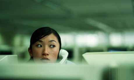 A businesswoman looking over a computer in office on telephone