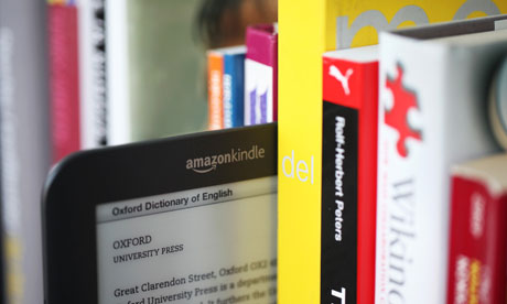 A Kindle alongside some paper books