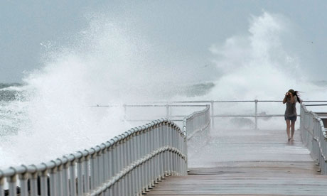 A person walks along a jetty in Florida as Hurricane Sandy passes offshore