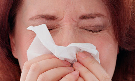 A woman sneezing into a tissue