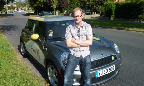 Mark King relaxes on the bonnet of a BMW Mini E 