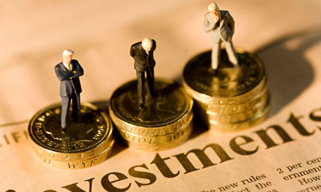 Miniature businessmen standing on stacks of coins on financial newspaper with investments