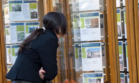 Young woman looking at houses in estate agent window