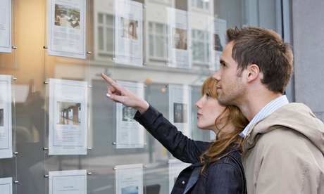 Couple looking in window outside estate agents 