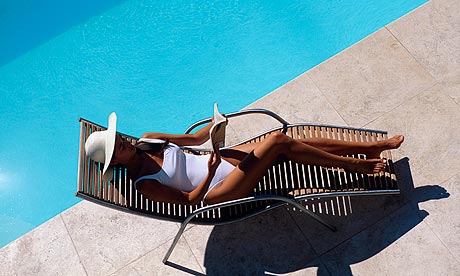 Woman reading by a swimming pool