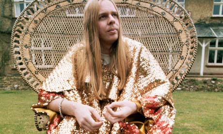 Rick Wakeman of Yes sits on a wicker chair wearing a glittering gold lame bathrobe