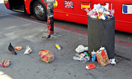 Overflowing litter bin beside London tour bus stop