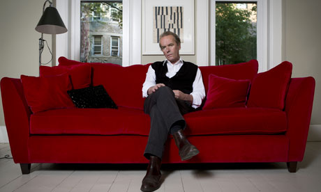 Martin Amis sitting on red sofa, at home in New York