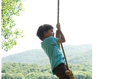 Boy hanging from rope over river