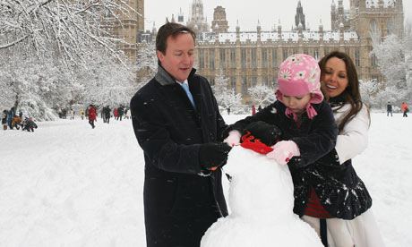 David Cameron and Carol Vorderman help a child build a snowman near the Houses of Parliament