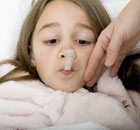 A girl lying in bed unwell with a thermometer