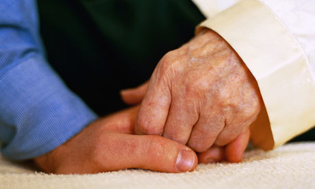 Dementia carer holding hands with patient A dementia carer holds the hand of 